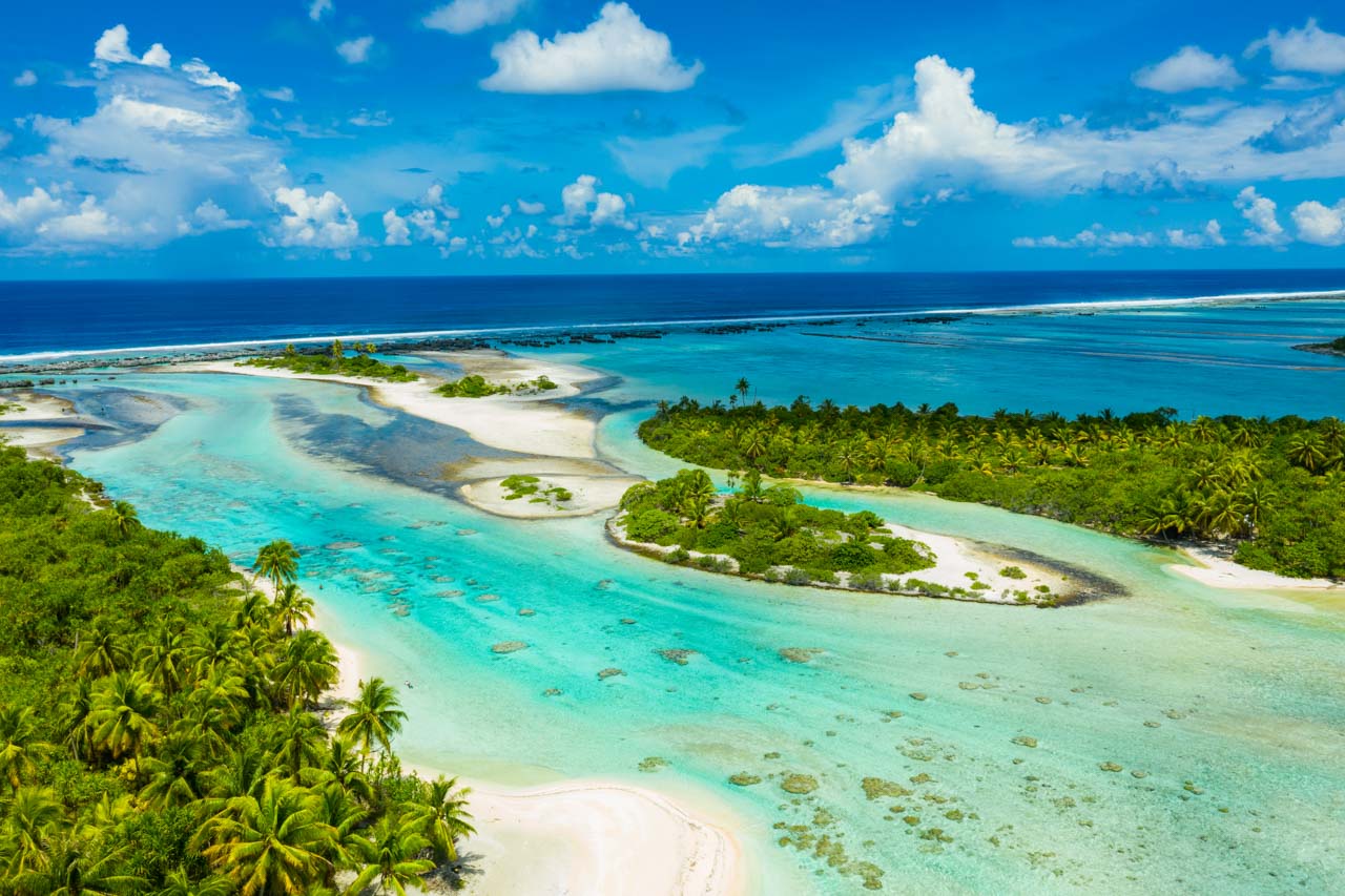Vivid aerial view of the coral islets and shallow blue channels of Tikehau Atoll in French Polynesia.