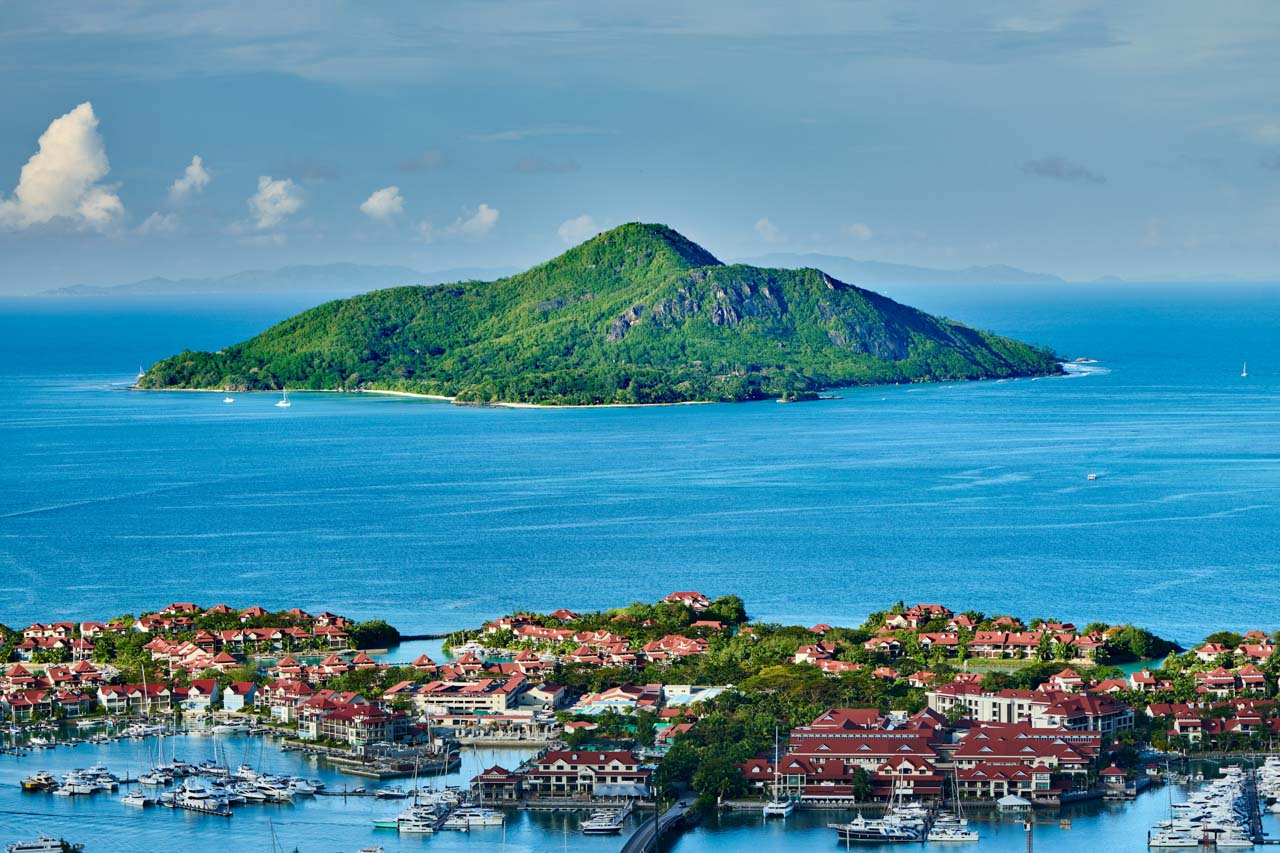 View of Sainte Anne Island from Eden Island with red-roofed villas and moored yachts in Seychelles.