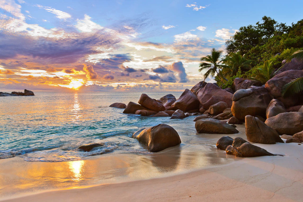 Sunset over granite boulders and golden shoreline at Anse Source d’Argent in Seychelles.